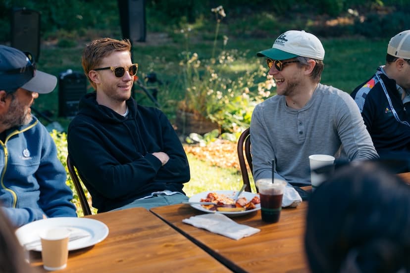 Austin arms crossed talking at table at NextView retreat